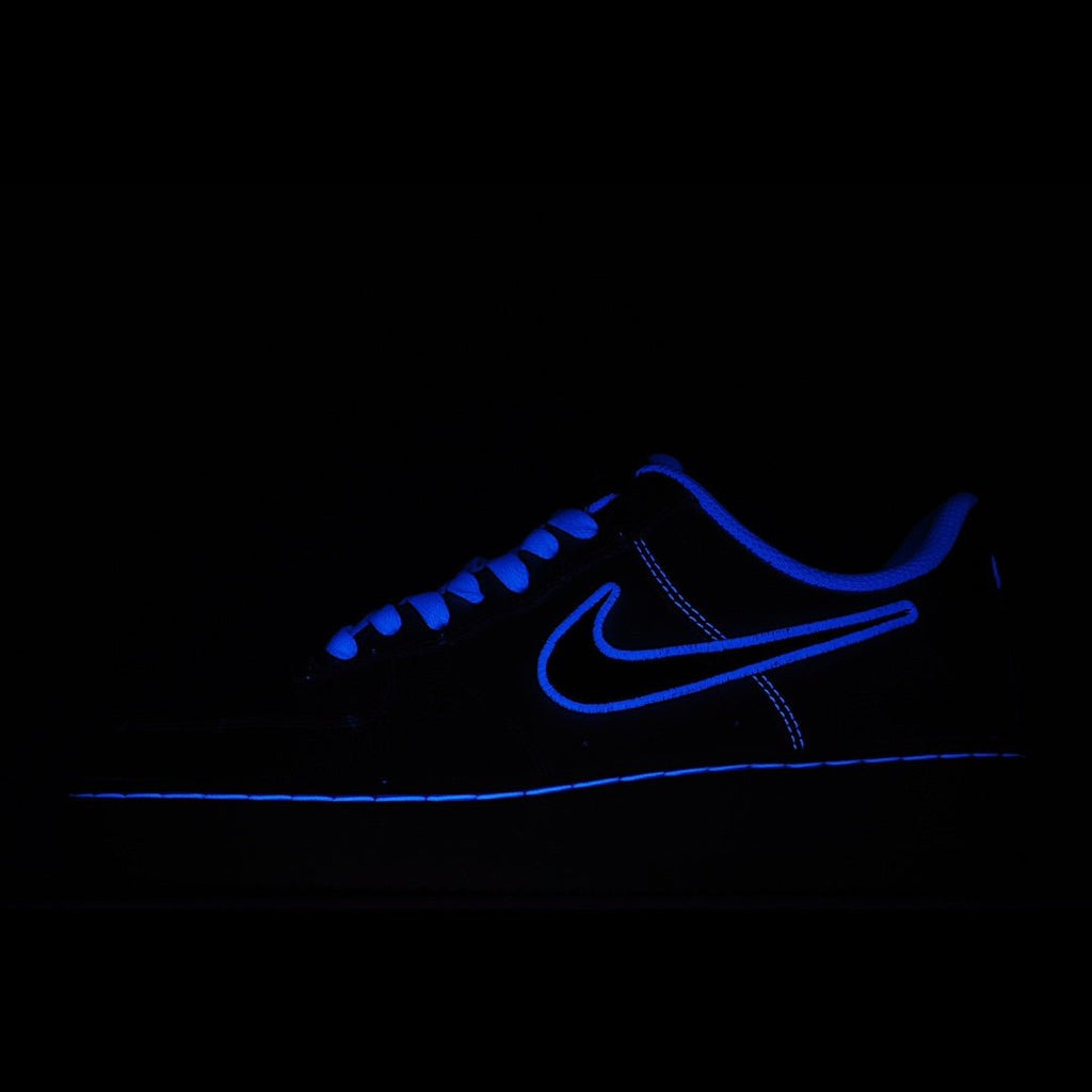 Low-top sneakers with blue laces, dark blue upper and glowing blue swoosh