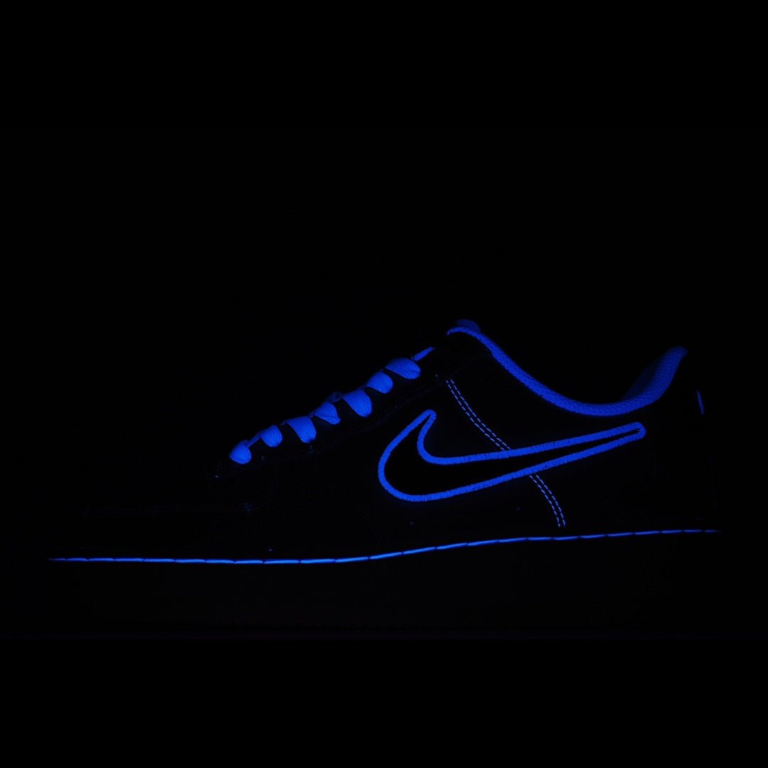 Low-top sneakers with blue laces, dark blue upper and glowing blue swoosh