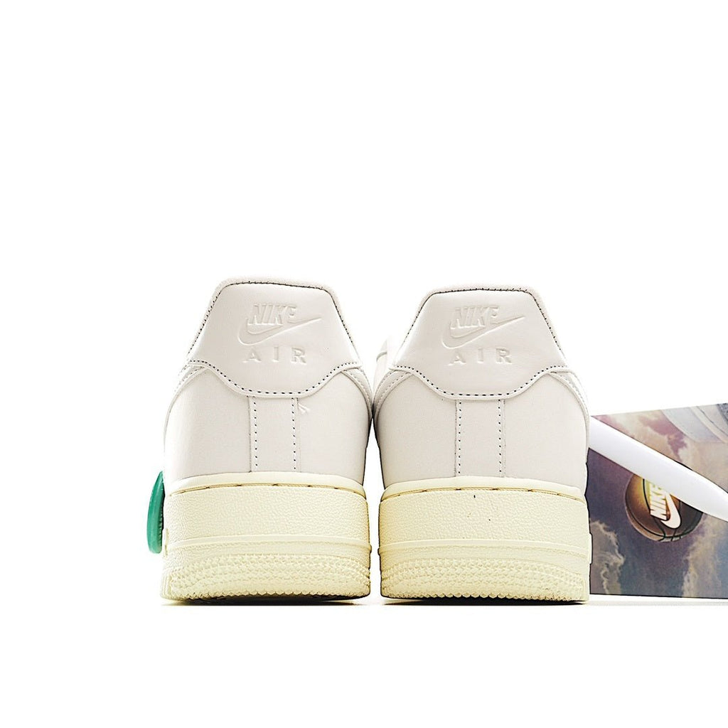 White low-top sneaker heel view with cream sole and green accent