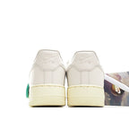 White low-top sneaker heel view with cream sole and green accent