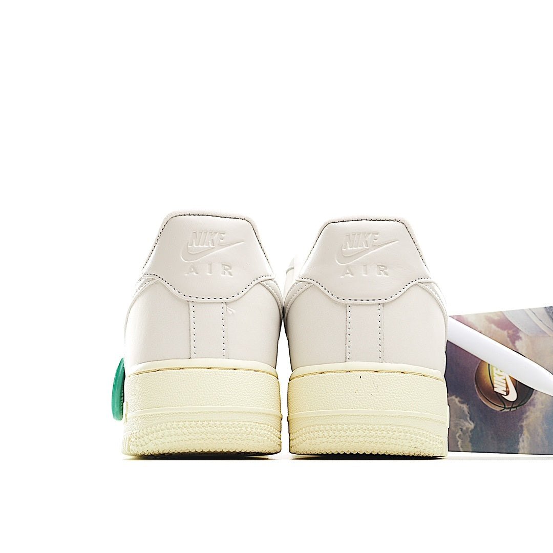 White low-top sneaker heel view with cream sole and green accent