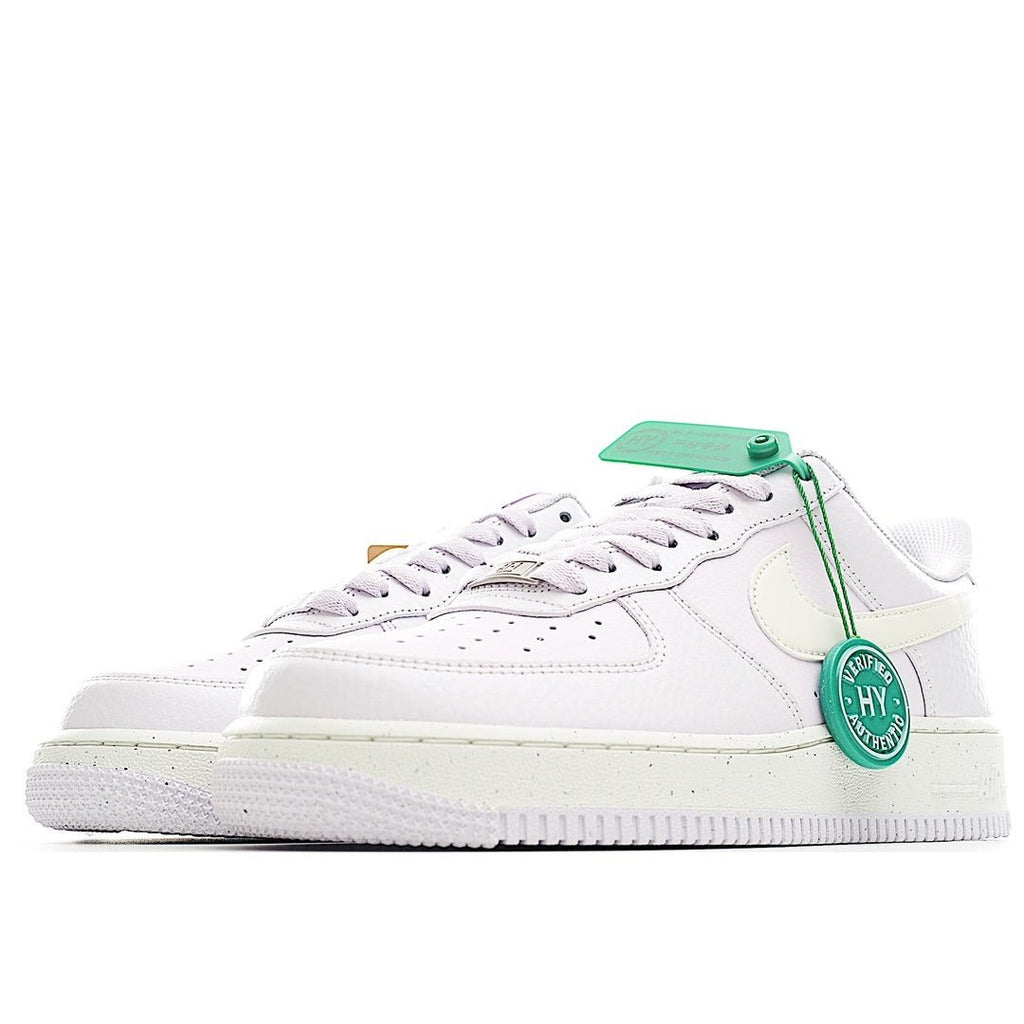 White low-top sneakers with pale yellow accents and green tag on lace area