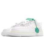 White low-top sneakers with pale yellow accents and green tag on lace area