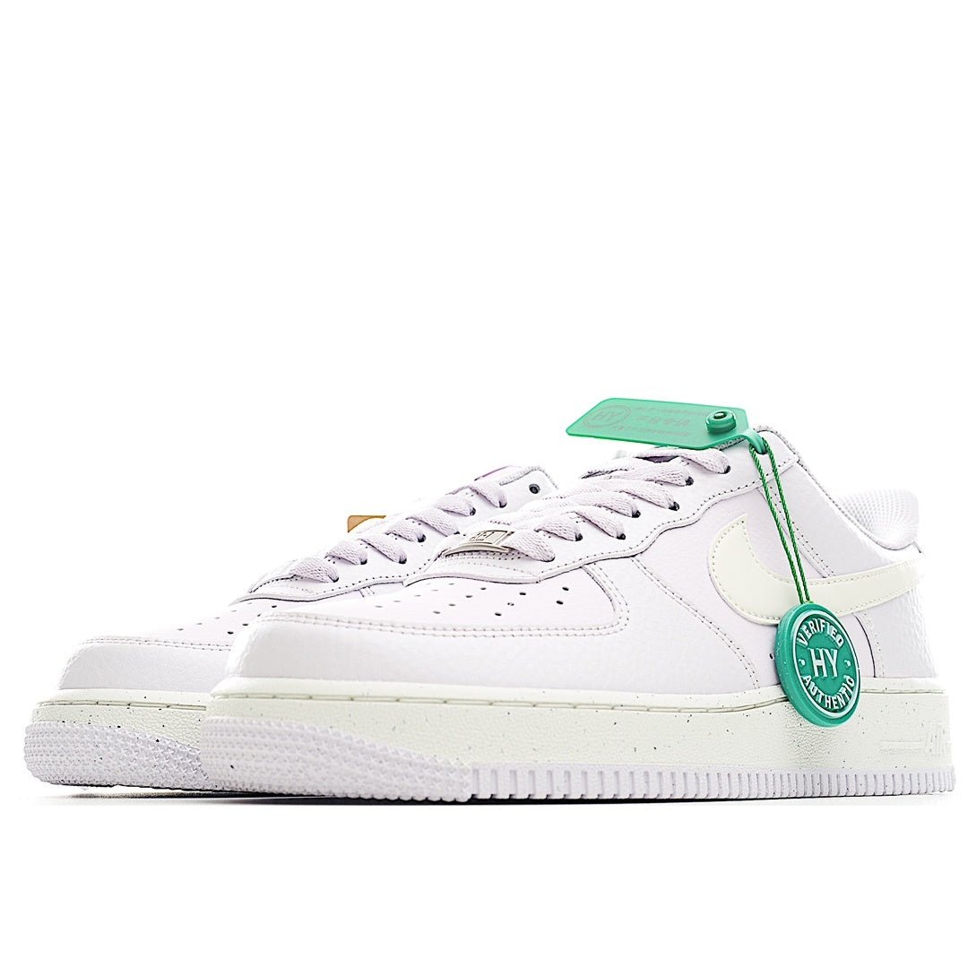White low-top sneakers with pale yellow accents and green tag on lace area