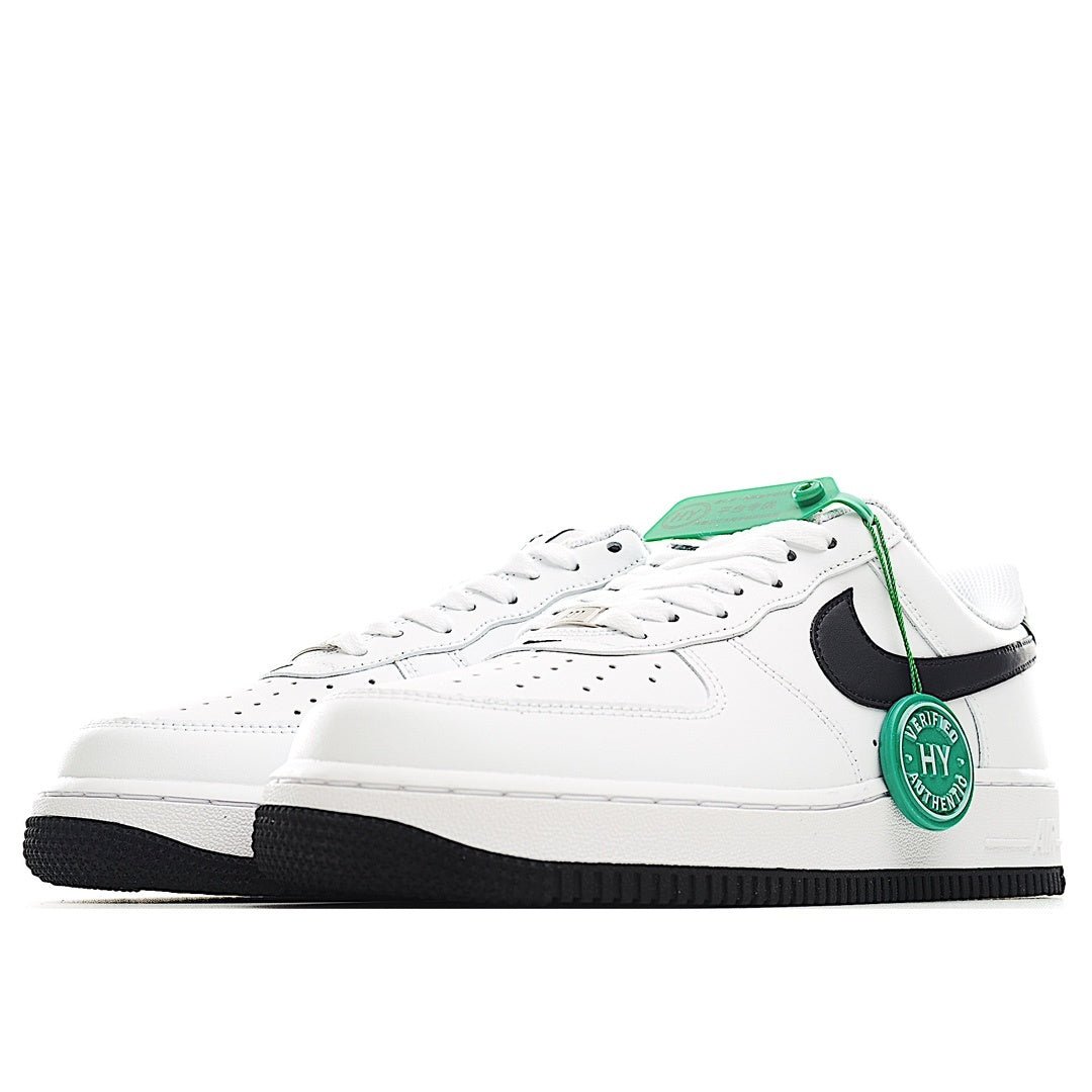 White low-top sneaker with black swoosh and green lace pull tab, angled view