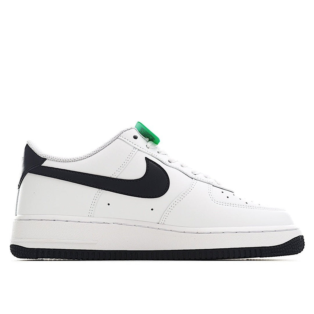 White low-top sneaker with black swoosh and green lace accent, profile view