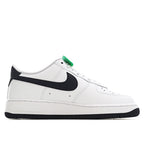 White low-top sneaker with black swoosh and green lace accent, profile view