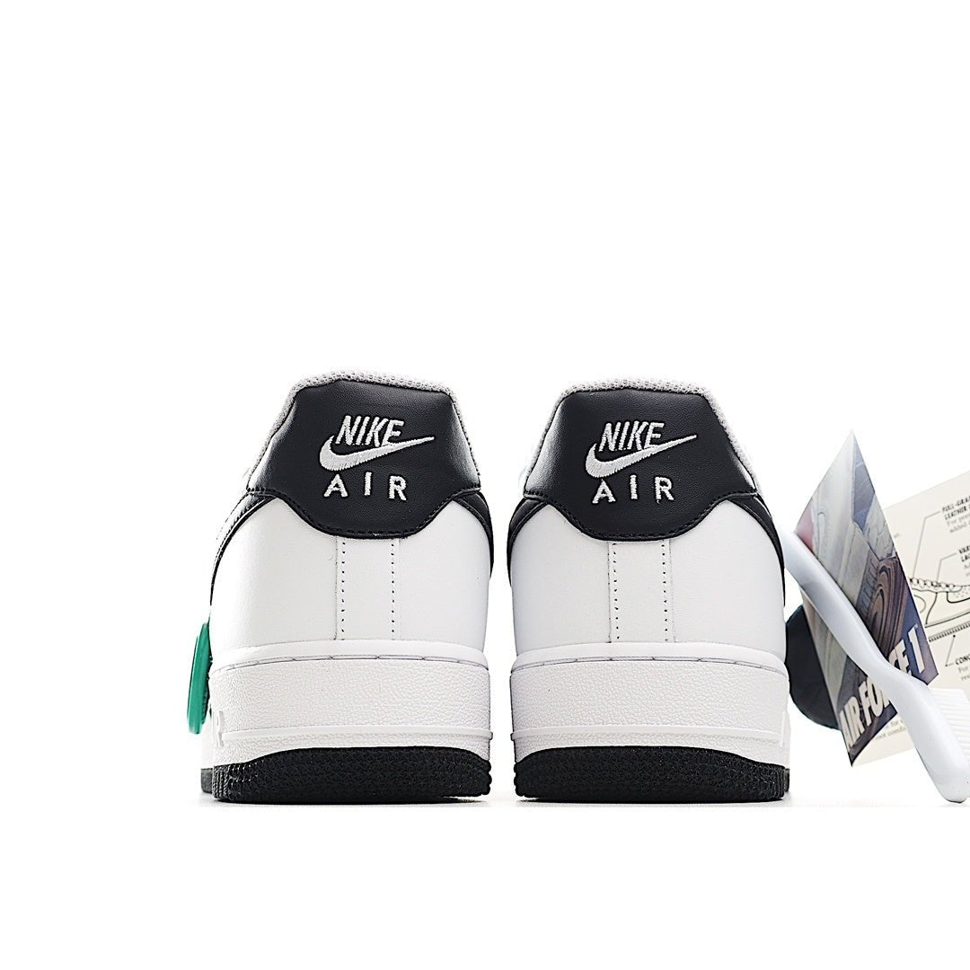Pair of white sneakers with black heel collars and green lace accents, back view