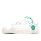 White low-top sneakers with light blue swoosh, green tag, and speckled midsole