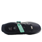 Nike Air Force 1 Low black sneaker with green tag, toe perforations visible