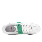 White low-top sneaker with green lacing tag and open interior showing sole lining