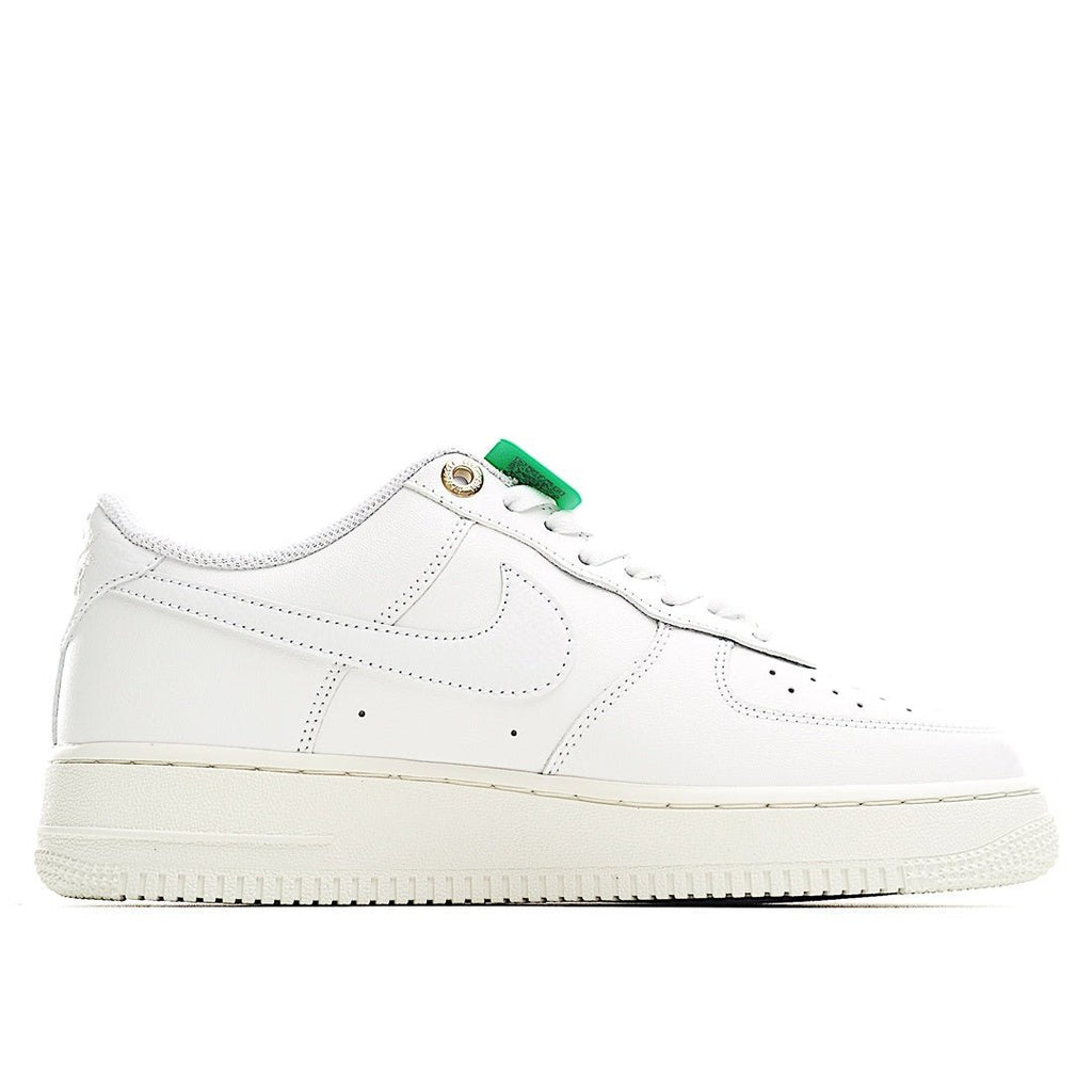 White Nike Air Force 1 low sneakers with gold eyelets and green lace tab