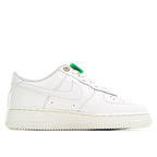 White Nike Air Force 1 low sneakers with gold eyelets and green lace tab