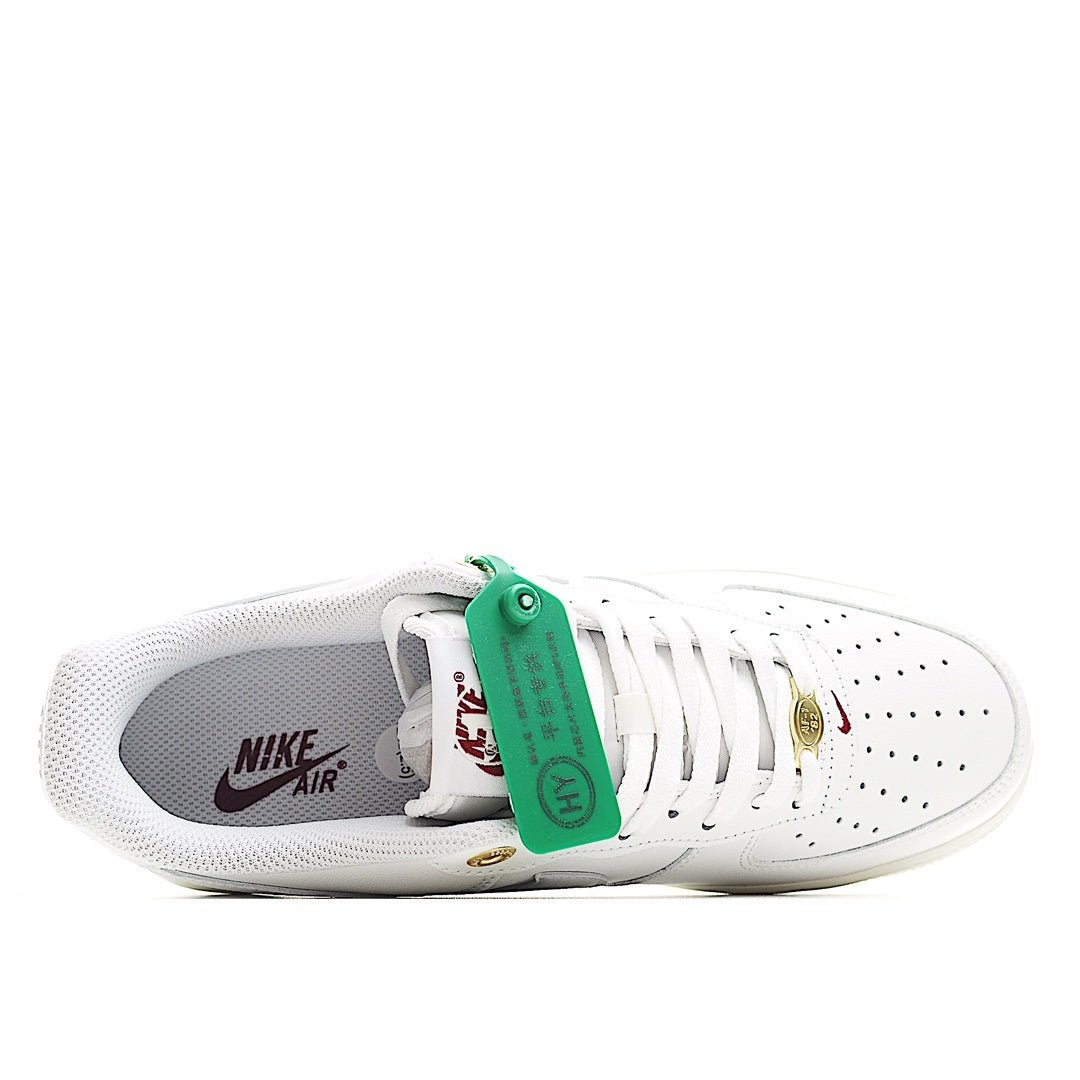 White Nike Air Force 1 low sneakers with Nike Air logo and green heel tag