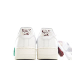 White Nike Air Force 1 low sneakers, back view, green lace pull and heel details