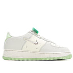White low-top sneakers with green lace accents, swoosh logo, and flat textured sole