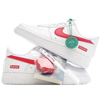 White low-top sneakers with red swoosh and green authenticity hang tag, angled view