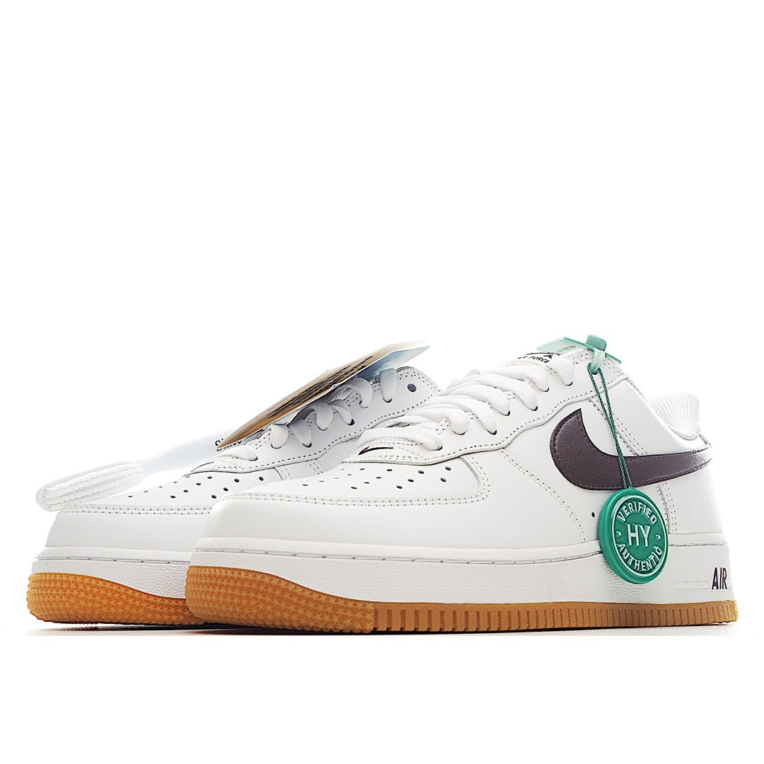 White low-top sneaker with dark swoosh, green tag, and tan gum sole