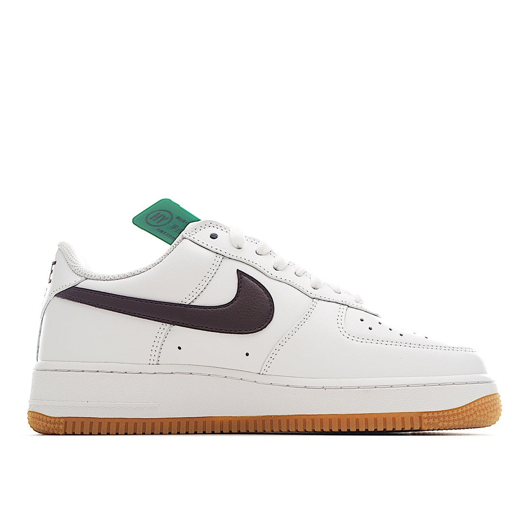 White low-top sneaker with dark swoosh and tan gum sole, green hang tag
