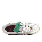 White Air Force 1-style sneakers with maroon interior lining and green hang tag