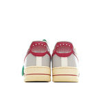 White Air Force 1-style sneakers with red heel accents and green hang tag