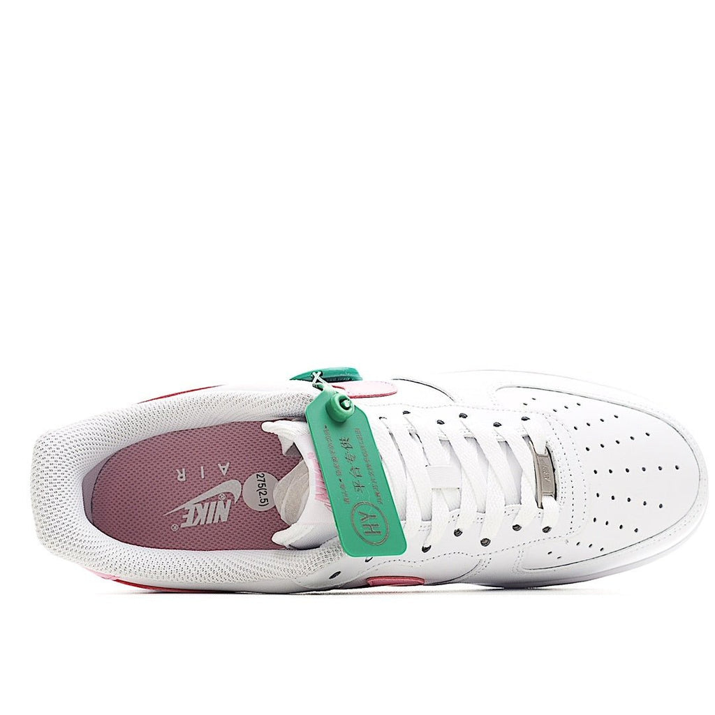White Nike Air Force 1 sneakers with pink heel panel and green hang tag
