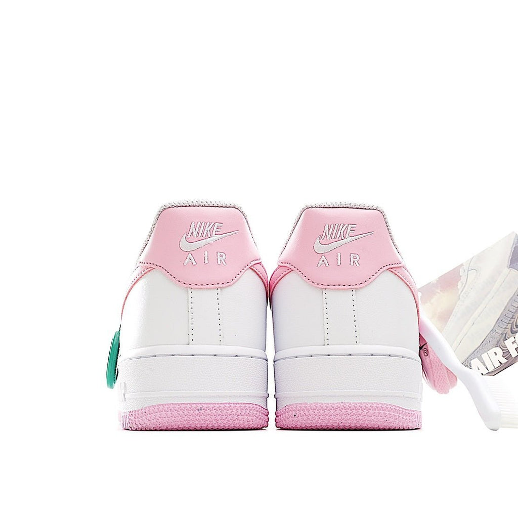 White Nike Air Force 1 sneakers with pink heel accents and green tag