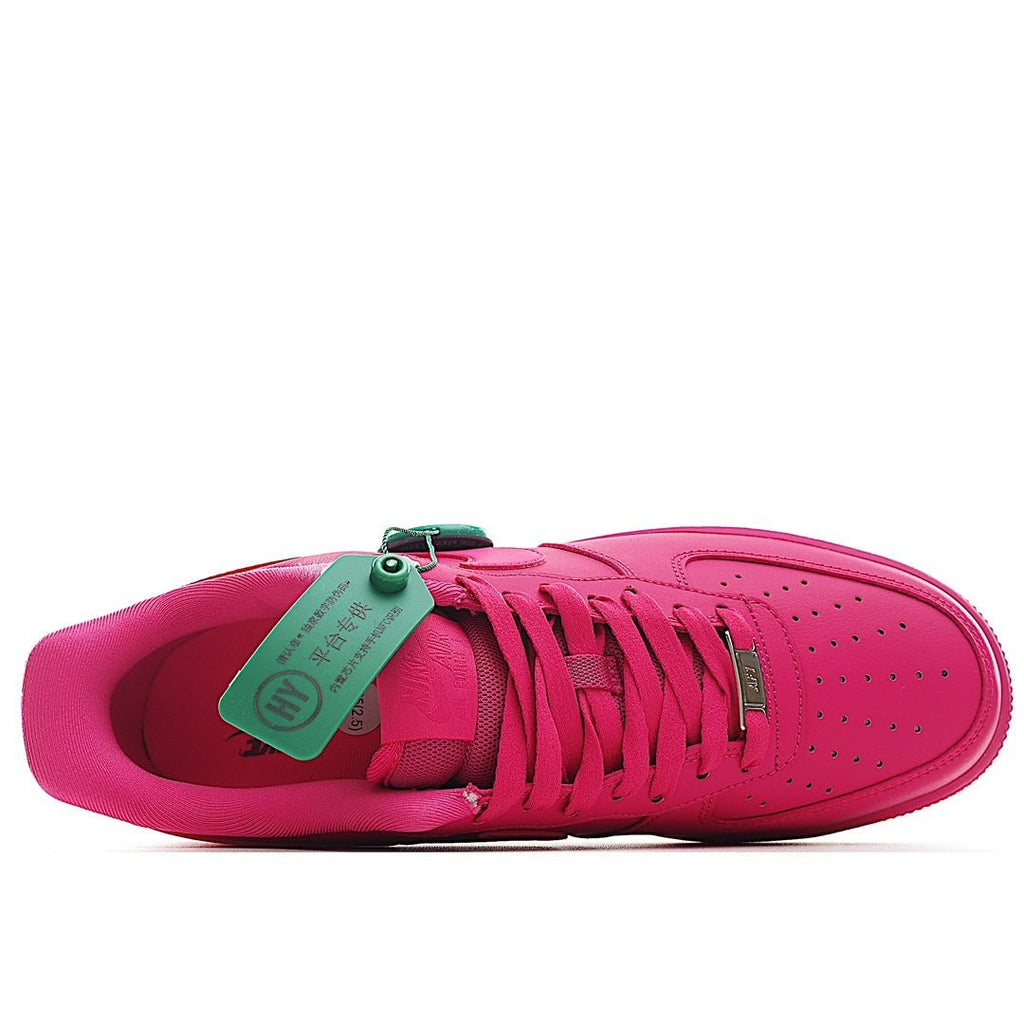 Pink Nike Air Force 1 low-top sneaker with green tag at tongue
