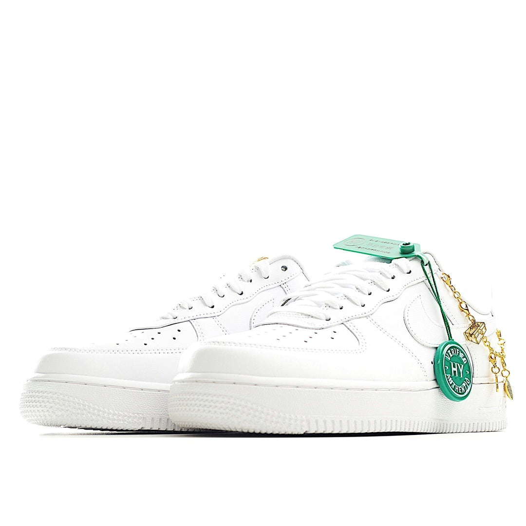 White low-top sneakers with green tag and gold chain detail, angled side view
