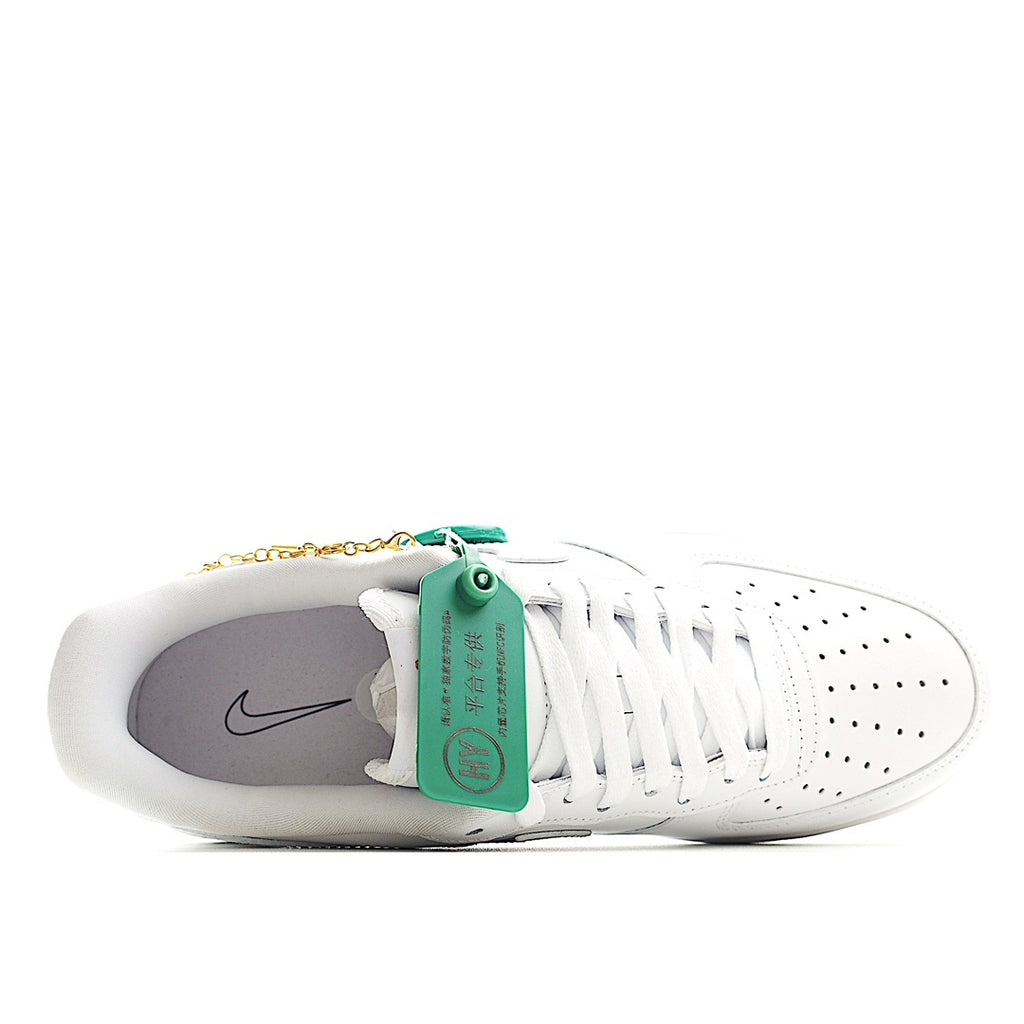 White low-top sneakers with green tag and gold chain charm, side view
