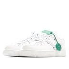 White low-top sneakers with green lace tips and side strap