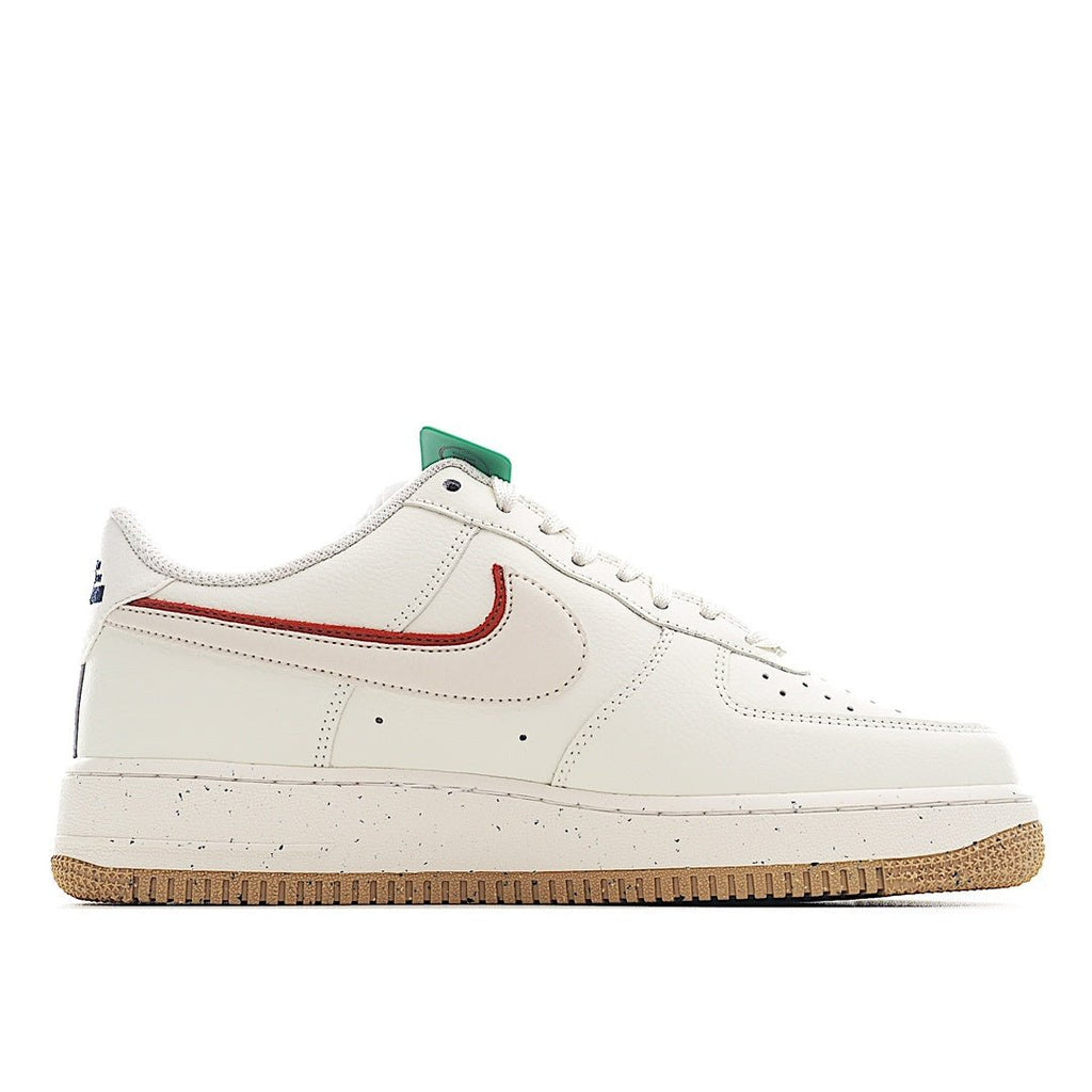 White Nike Air Force 1 sneaker front quarter view with red swoosh, green lace tag, gum sole