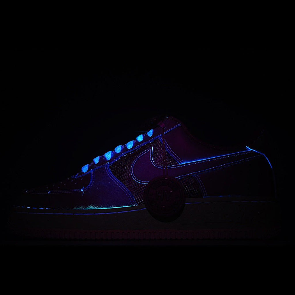 Low-top sneakers with dark upper and blue glowing swoosh accents
