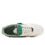 White and green low-top sneakers, heel view with laces and green collar padding.