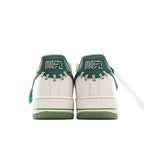 White and green low-top sneakers, back view with green heel tab and lace loops.