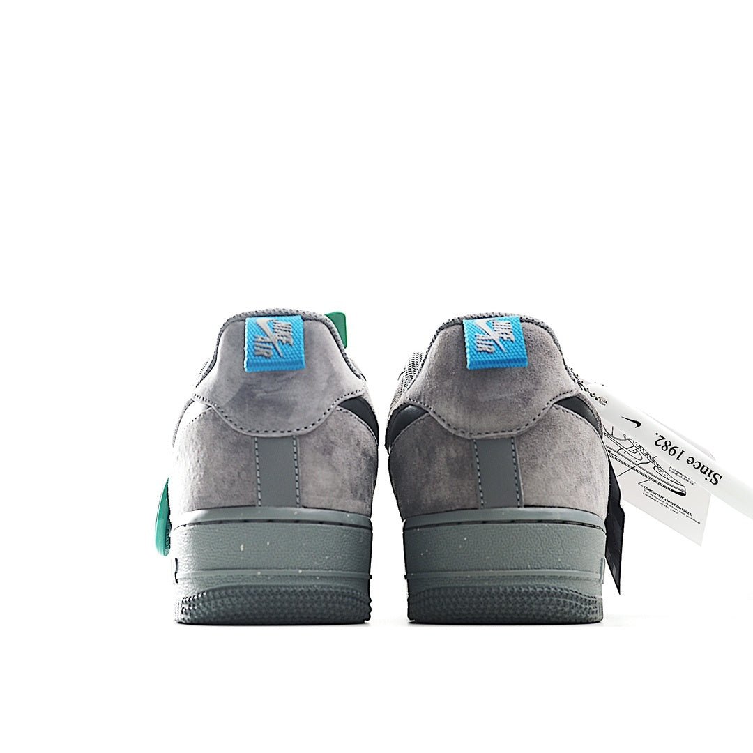 Grey Nike Air Force 1 sneakers with heel details, green tongue tag, and blue lace pull