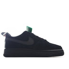 Black low-top sneaker with red swoosh, dark panels, and green tag on tongue