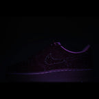 Dark sneaker with faint swoosh logo and glow-like purple outline