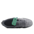 Gray sneakers showing lace area and green tongue tag, with black interior