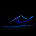 Low-top sneaker with dark upper, blue Swoosh, and glowing blue outsole edge