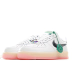 White low-top sneaker side view with green accents, black swoosh, and pink sole