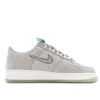 Light gray low-top sneakers with white swoosh and perforated toe, green collar
