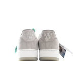 Light gray low-top sneakers with Nike Air branding on heel and green lace pull