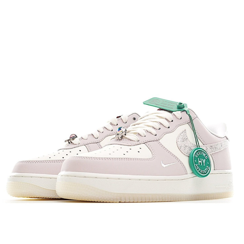Low-top sneaker in pale pink and white with green lace accents and perforated toe.
