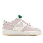 Low-top sneaker side view in pale pink and white with green heel detail.