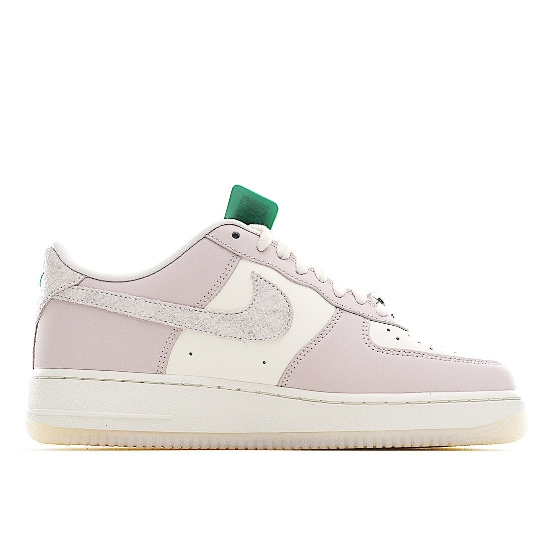 Low-top sneaker side view in pale pink and white with green heel detail.