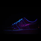Low-top sneaker in dark blue with purple swoosh and blue lace detailing.