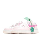 Pink and white low-top sneakers with laces and green hang tag
