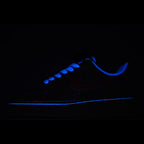 Low-top sneakers with blue glowing accents in dark lighting