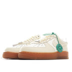 Cream leather low-top sneaker, green lace lock tag, tan gum sole